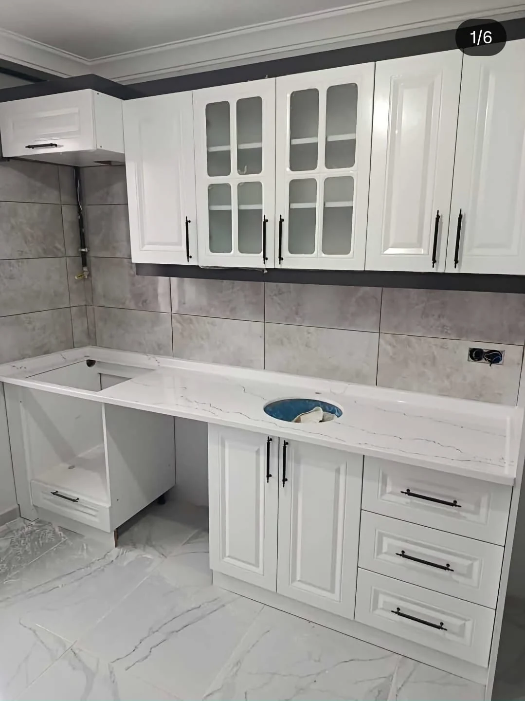 Klasik mutfak kurulum görüntüsü. Cam detaylı üst dolaplar, çerçeve kapaklar ve boş tezgâh açıklıkları mutfak kurulum aşamasında görülüyor.